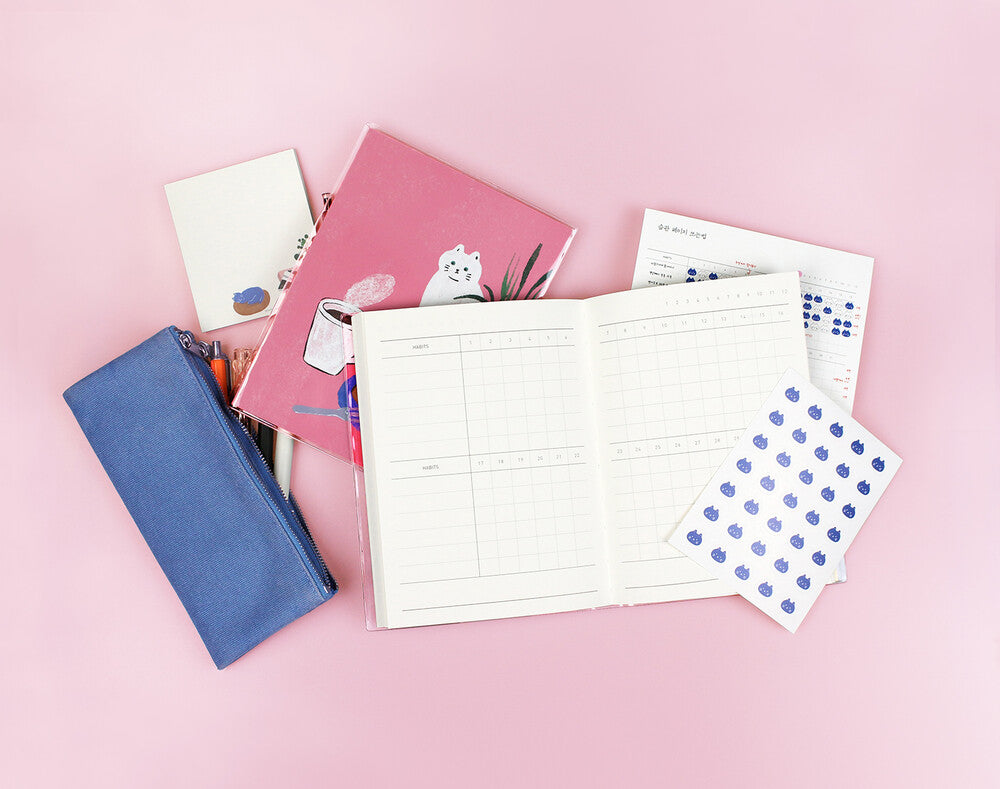Collection of stationery items including notebooks and a blue pouch on a pink background